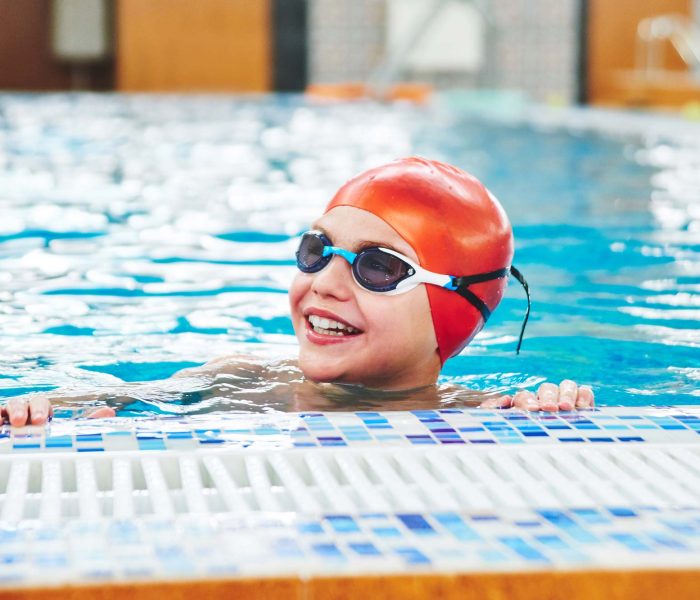 joyful-smiling-boy-swimmer-cap-goggles-learns-professional-swimming-swimming-pool-gym-close-up